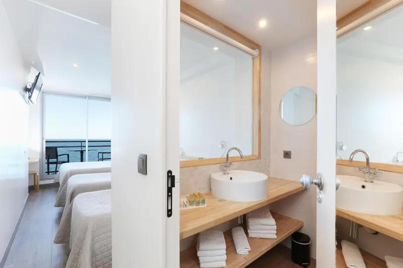 Une chambre lumineuse avec deux lits simples et une salle de bain moderne.