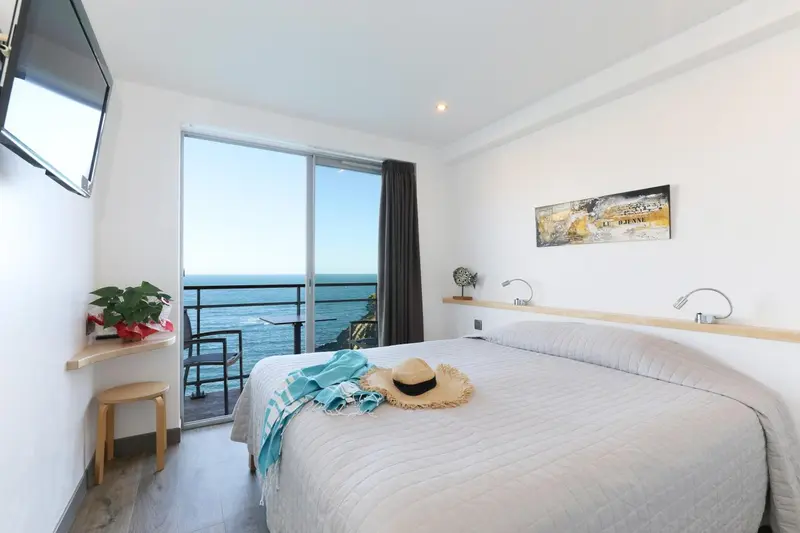 Une chambre lumineuse avec un grand lit donnant sur la mer.