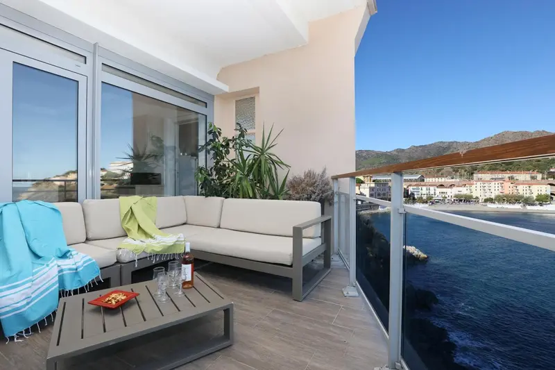 Terrasse aménagée avec canapé et table basse donnant sur la mer.