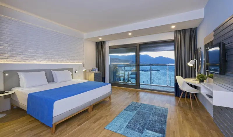 Chambre lumineuse avec un grand lit donnant sur une vue mer.