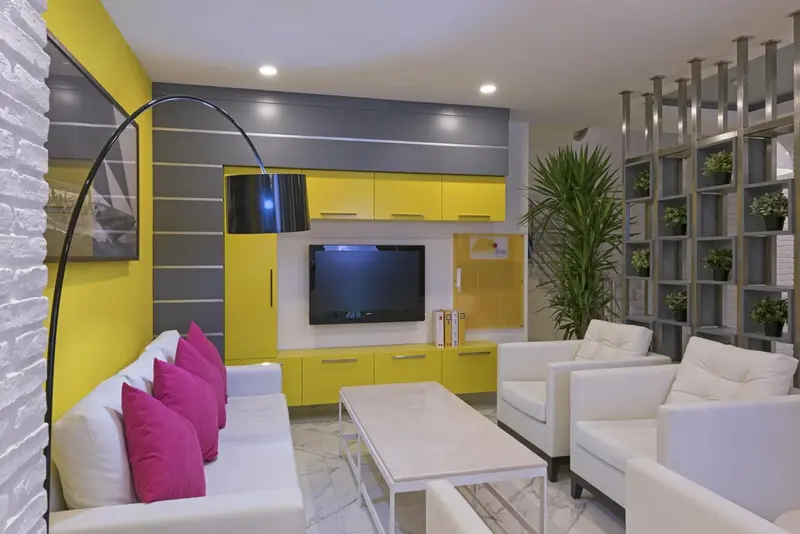 Un salon moderne avec un canapé blanc, des fauteuils et une télévision murale.