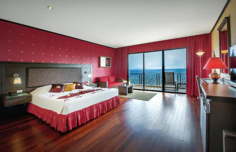 Chambre avec un grand lit et une vue sur la mer par une baie vitrée.