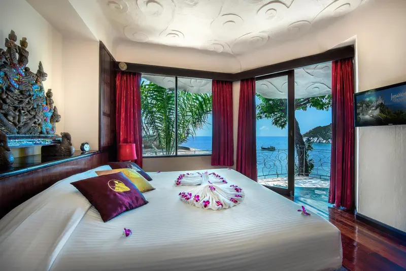 Une chambre avec un lit décoré de fleurs et une vue sur la mer.