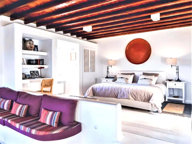Une chambre lumineuse avec un grand lit et un coin salon.
