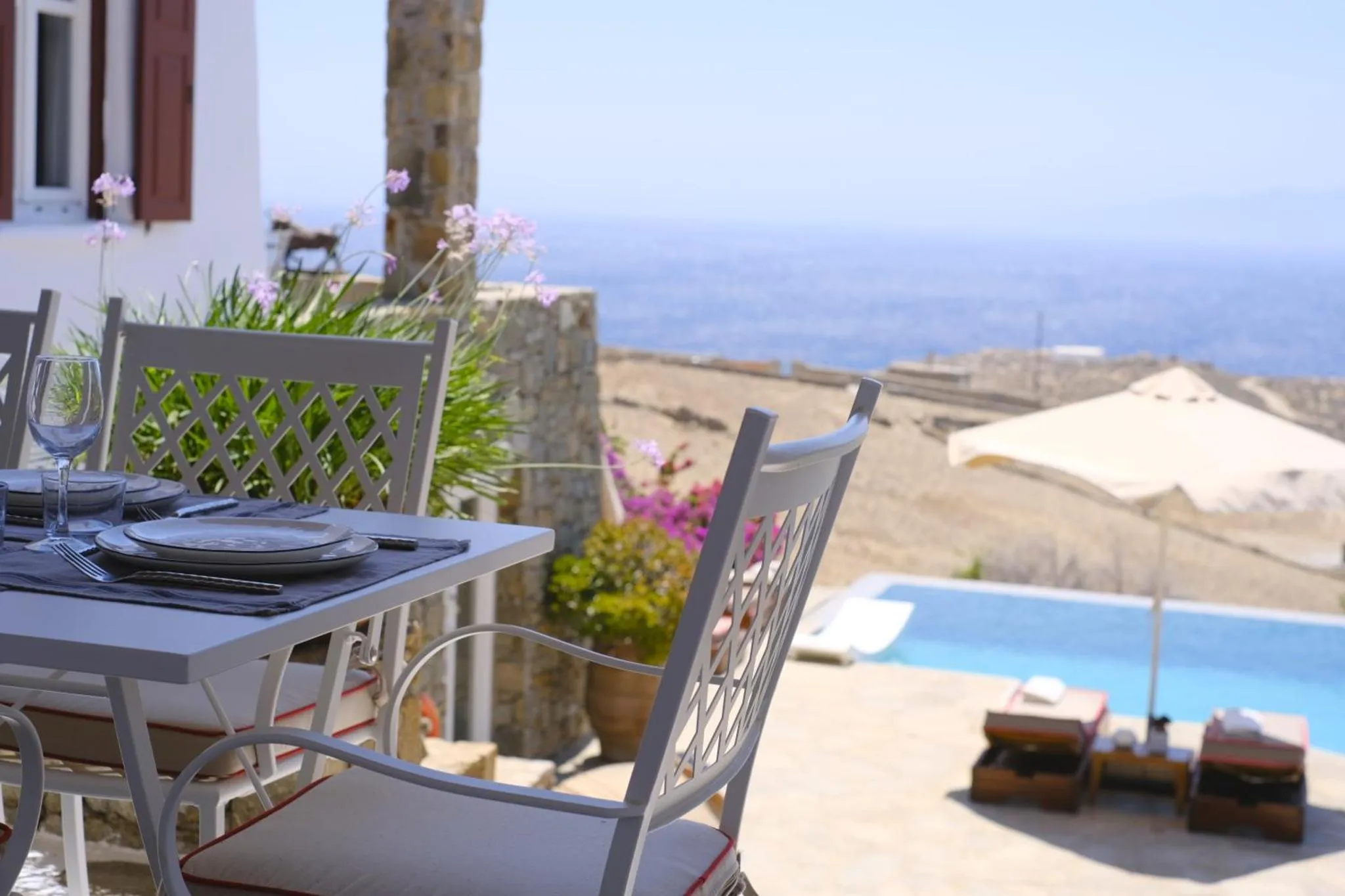 Table dressée sur une terrasse avec vue sur la mer et une piscine.