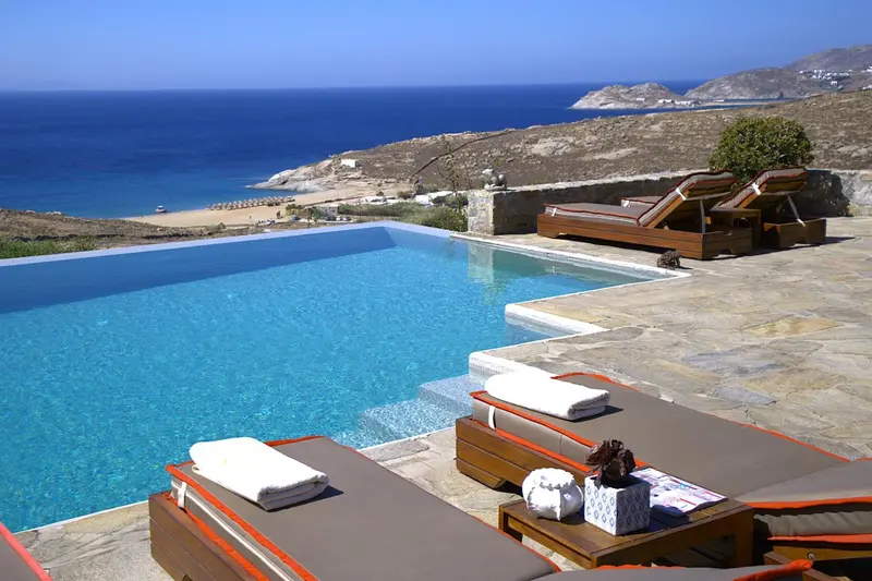 Transats et piscine à débordement avec vue sur la mer et le littoral.