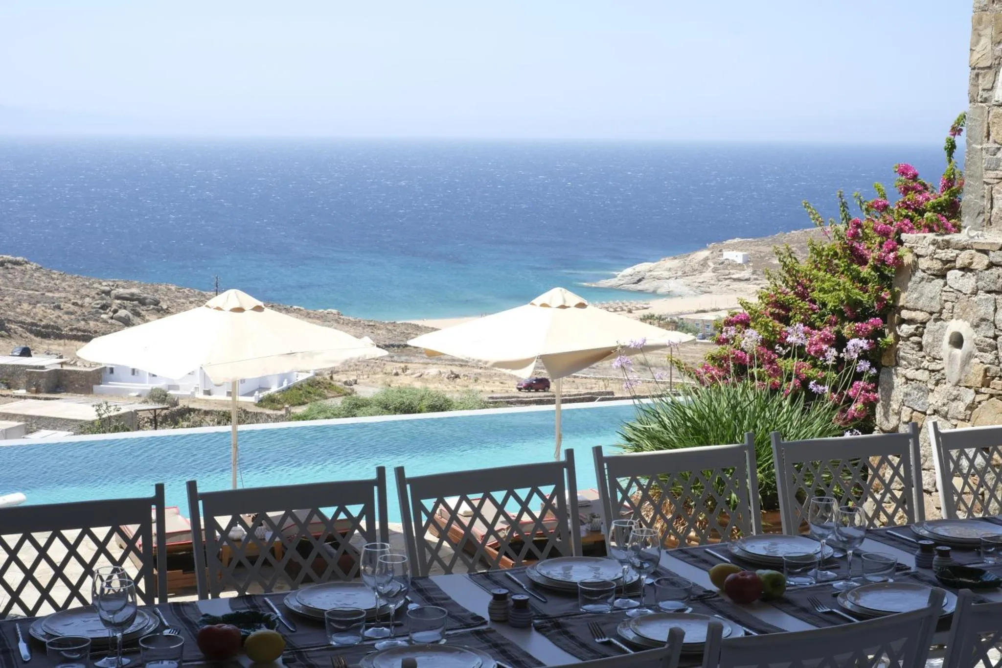 Une table est dressée devant une piscine avec vue sur la mer.