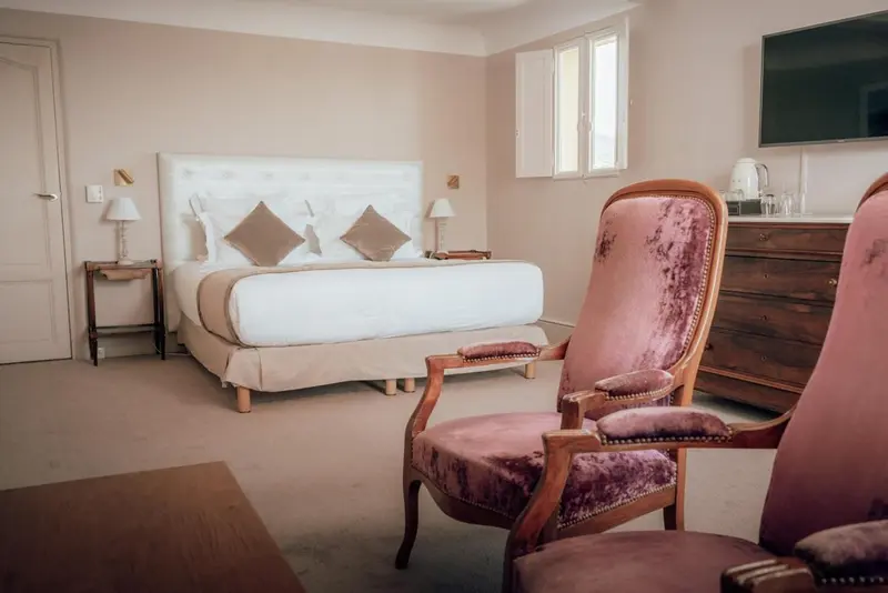 Une chambre à coucher lumineuse avec un grand lit et un fauteuil.