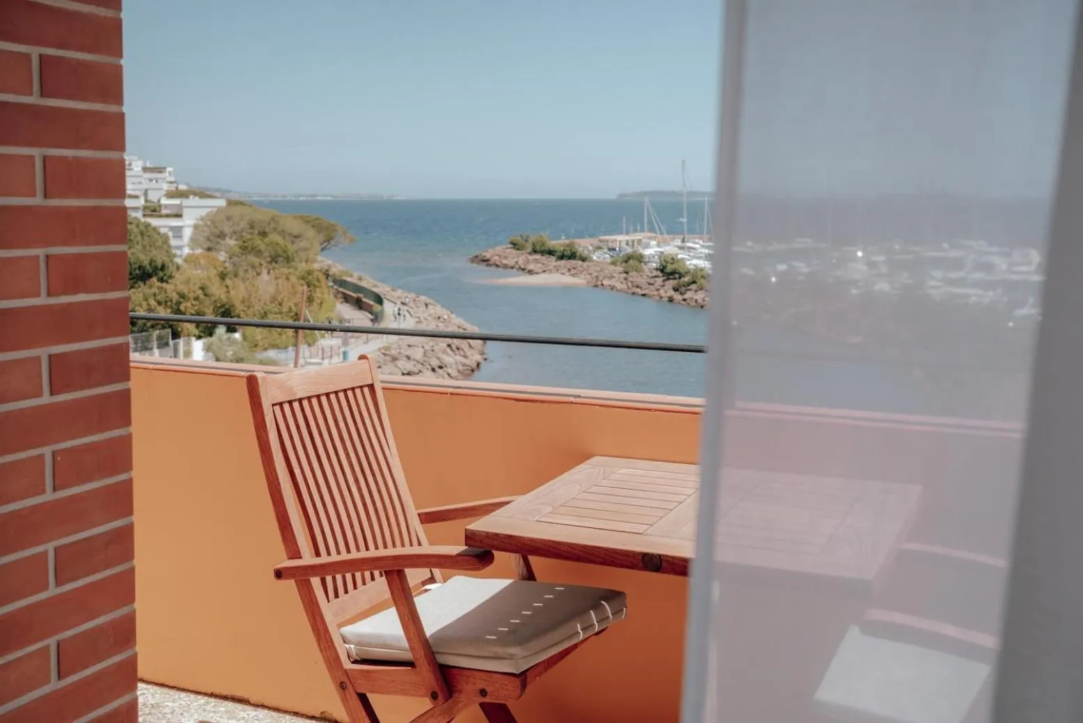 Une chaise en bois sur une terrasse donnant sur la mer.