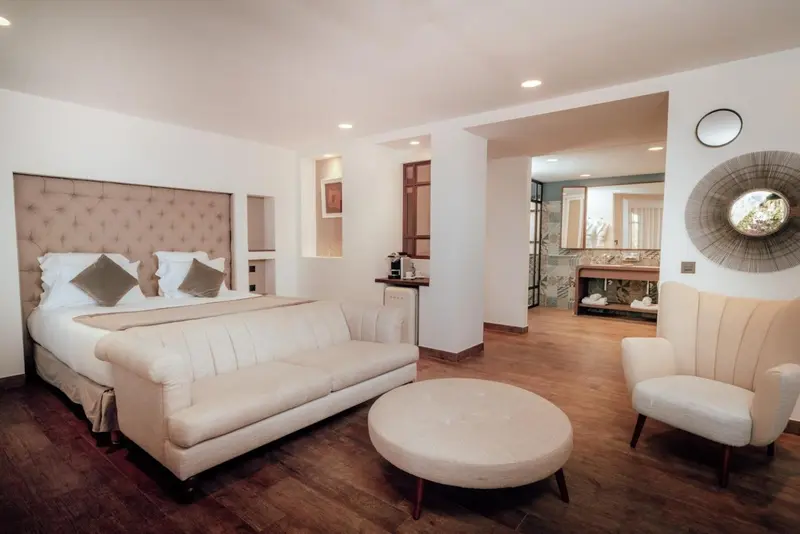 Une chambre lumineuse avec un grand lit et un espace salon.
