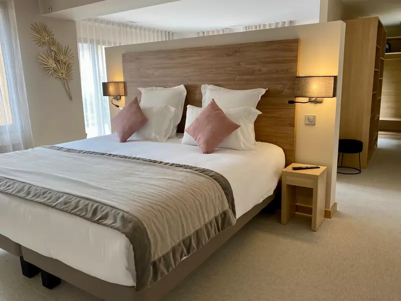Une chambre lumineuse avec un grand lit recouvert de coussins.
