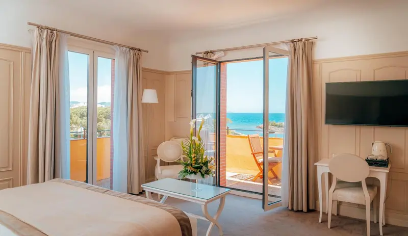 Une chambre lumineuse s'ouvre sur une terrasse avec vue sur la mer.