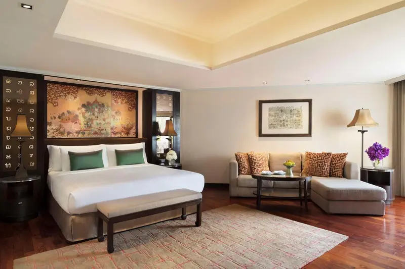 Une chambre lumineuse avec un grand lit et un coin salon.