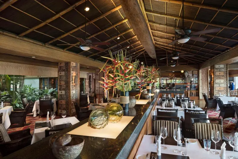 Une salle de restaurant spacieuse avec des tables dressées et une décoration florale.