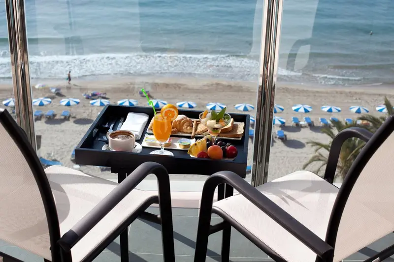 Un plateau de petit-déjeuner est servi sur une terrasse avec vue sur la plage.