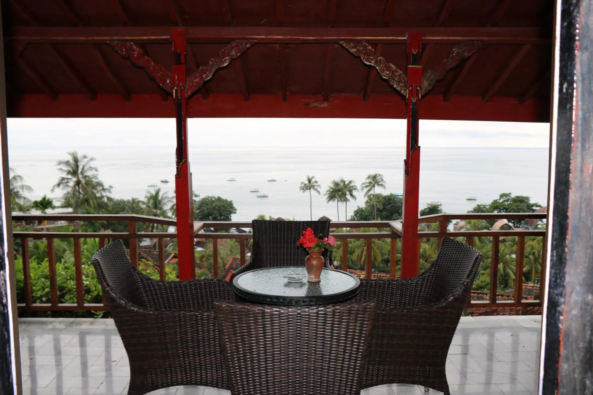Terrasse ombragée avec mobilier en rotin donnant sur la mer.