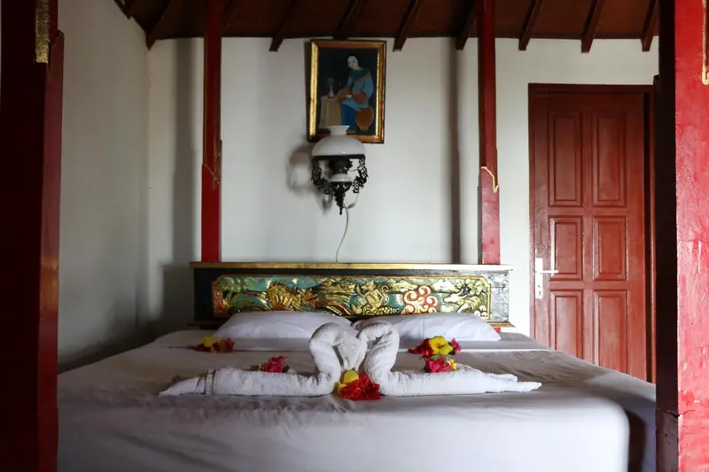 Un lit double est decoré de serviettes en forme de cygnes et de fleurs.
