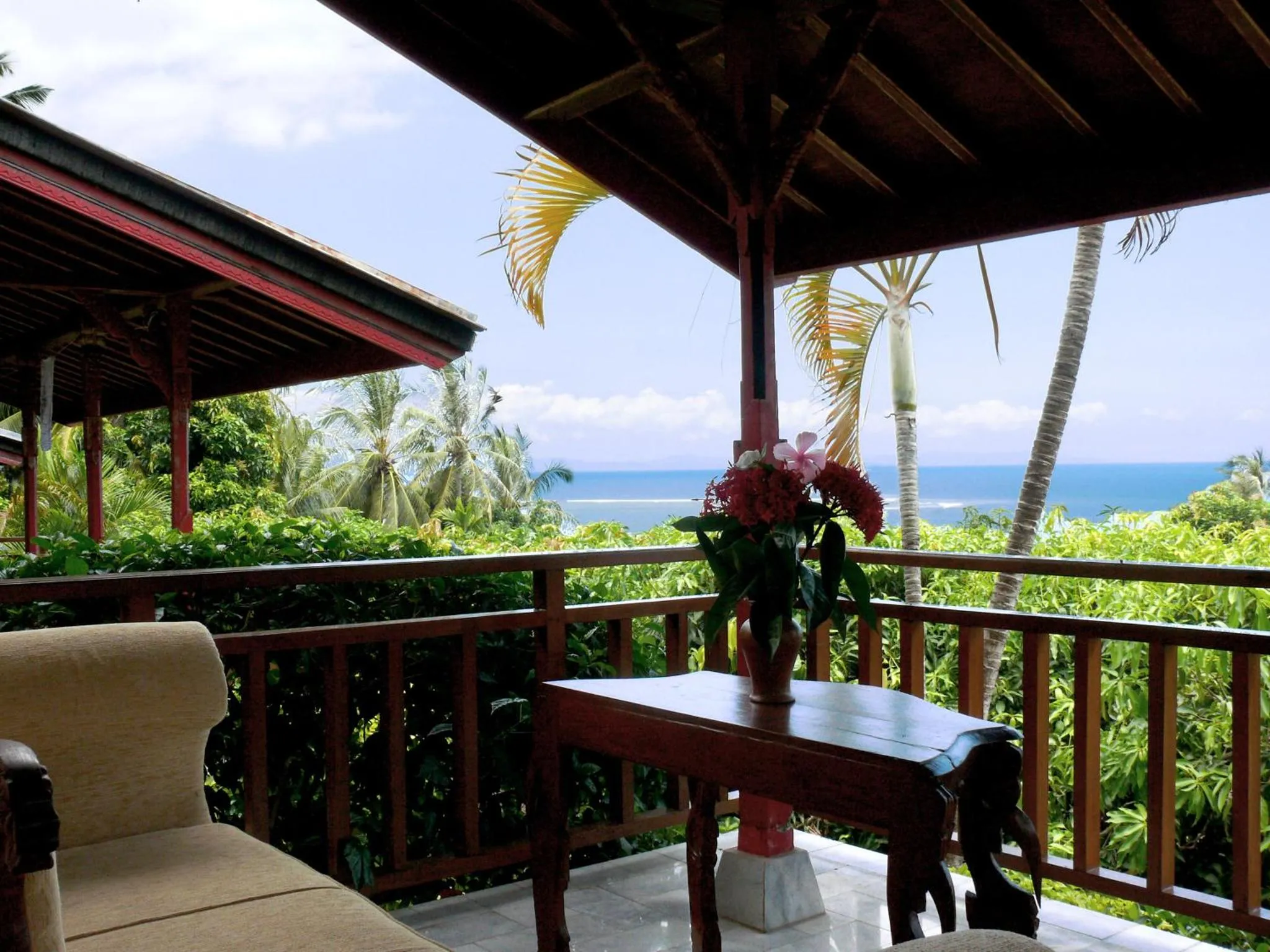 Terrasse ombragée avec mobilier et vue sur la mer.