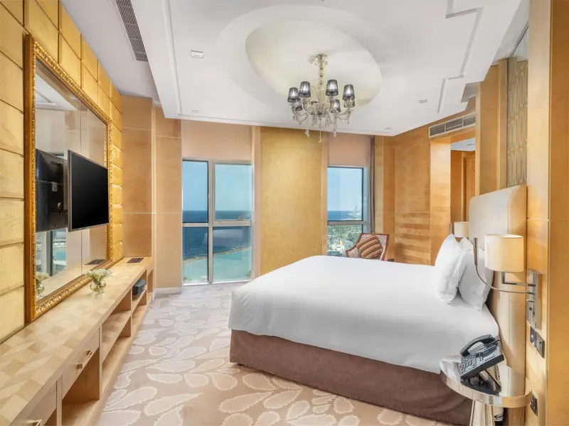 Chambre lumineuse avec un grand lit et une vue sur la mer.