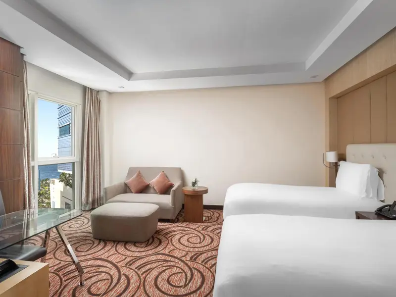 Une chambre lumineuse avec un canapé et deux lits simples.