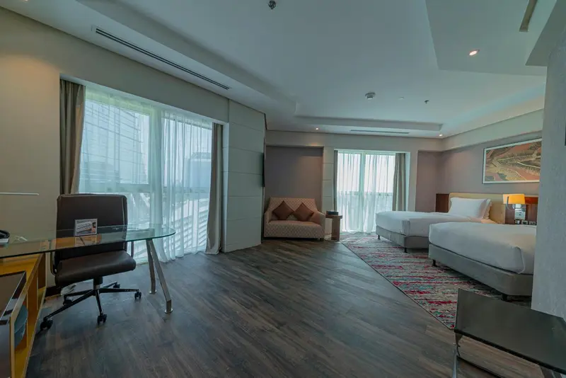 Une chambre spacieuse avec un bureau, un canapé et deux lits simples.