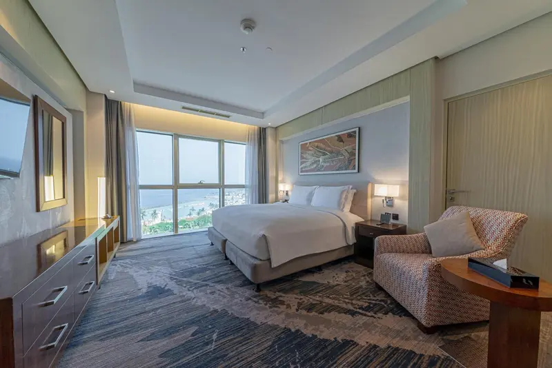Une chambre d'hôtel spacieuse avec un grand lit et un fauteuil.