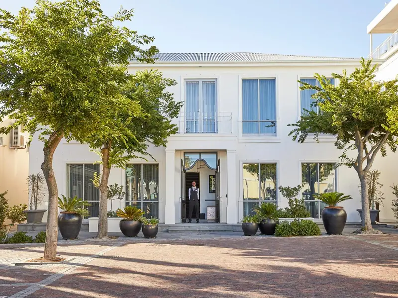 Façade blanche d'un bâtiment avec des arbres et une entrée.
