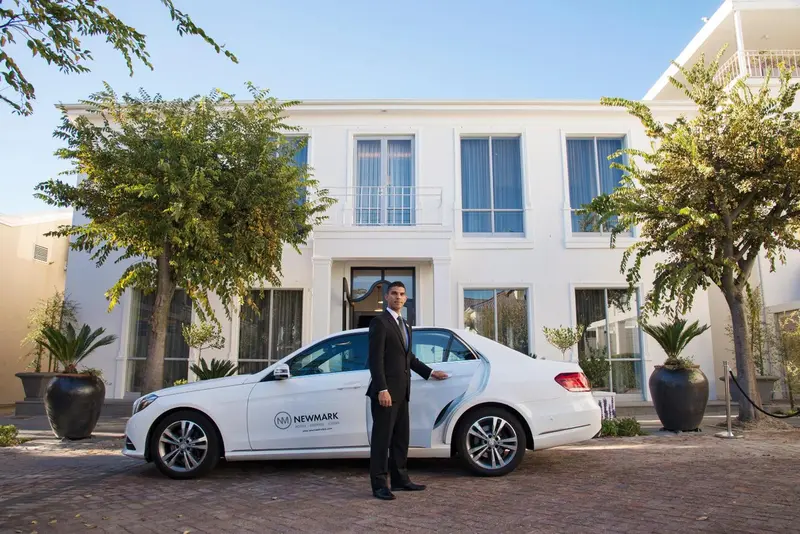 Façade d'un bâtiment blanc avec une voiture et un homme en costume.