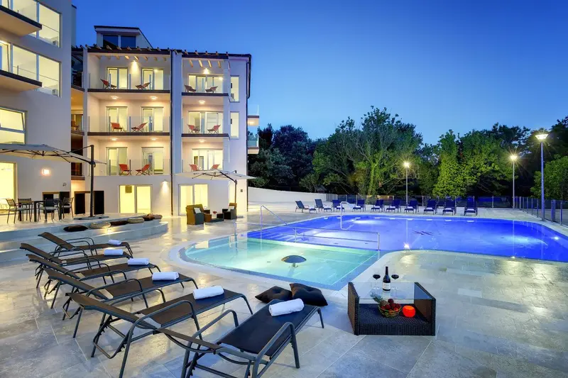 Transats et piscine au bord d'un bâtiment éclairé.