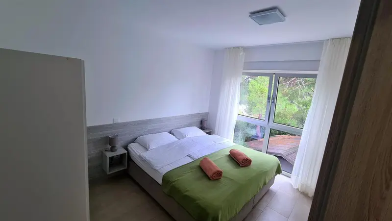 Une chambre lumineuse avec un lit double et une vue sur la végétation.