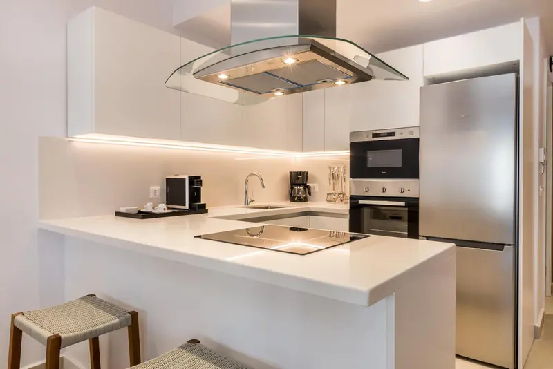 Une cuisine moderne avec un plan de travail blanc et des appareils en inox.