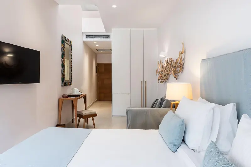 Une chambre lumineuse avec un lit fait et un canapé près d'un mur décoré.