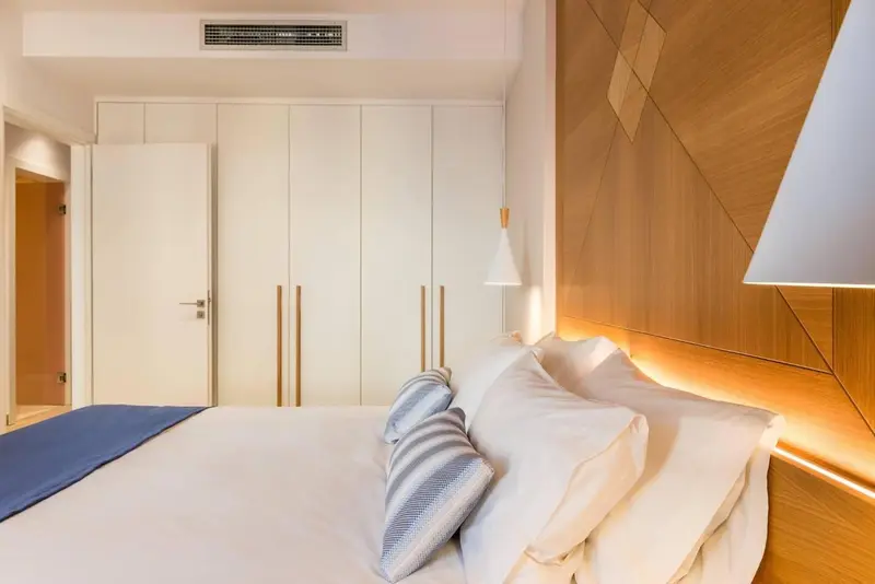 Une chambre lumineuse avec un grand lit et un mur décoratif en bois.