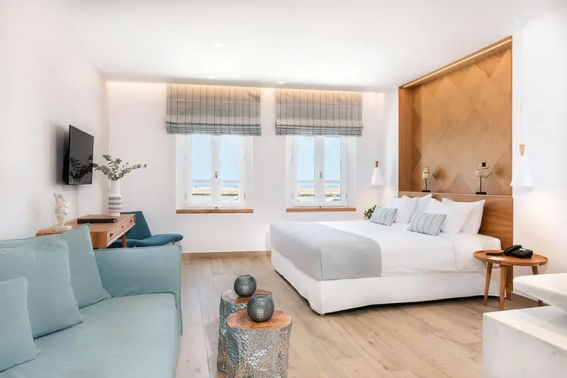 Une chambre lumineuse avec un lit double et un coin salon.