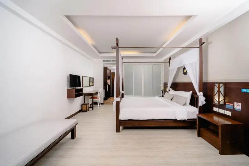 Une chambre lumineuse avec un grand lit à baldaquin et un espace détente.