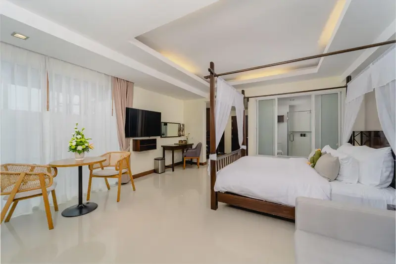 Une chambre lumineuse avec un lit à baldaquin et un coin repas.
