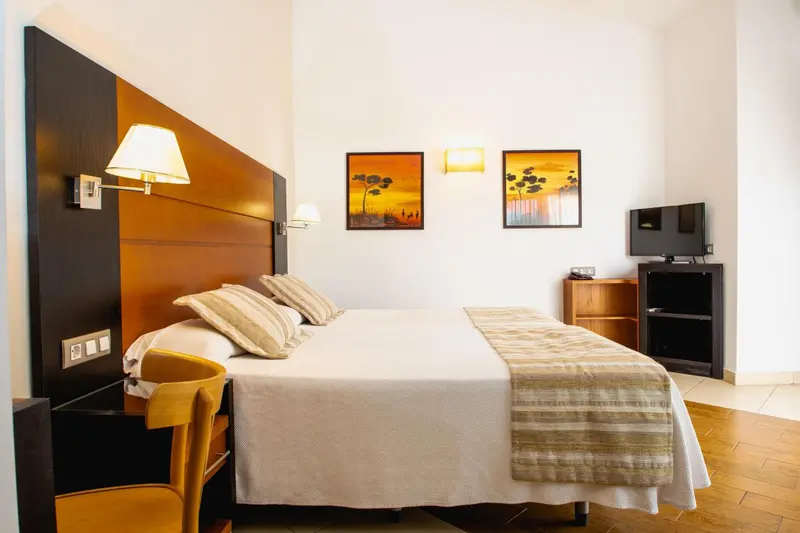 Une chambre lumineuse avec un grand lit et des tableaux décoratifs.