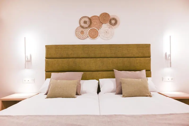 Une chambre avec un grand lit recouvert de coussins et d'une tête de lit verte.