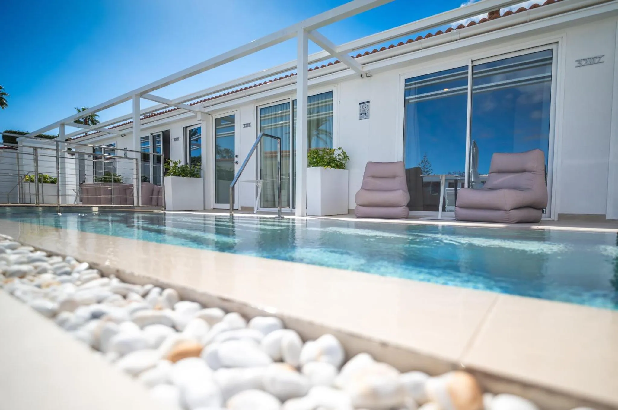 Terrasse avec piscine et mobilier de détente.