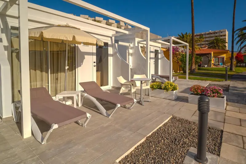 Terrasse avec transats et plantes fleuries devant des logements.