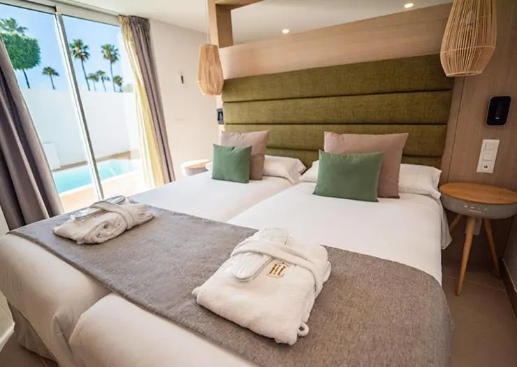 Une chambre lumineuse avec un grand lit et un accès à une piscine.