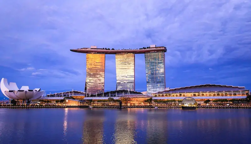 Bâtiment moderne avec une structure surélevée au bord de l'eau au crépuscule.