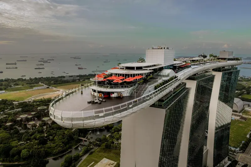 Vue aérienne d'une terrasse panoramique avec des parasols rouges et un restaurant sur le toit d'un bâtiment.