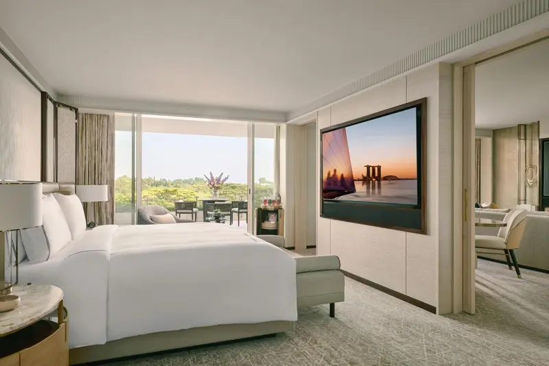 Chambre lumineuse avec un grand lit et une vue sur un paysage verdoyant.