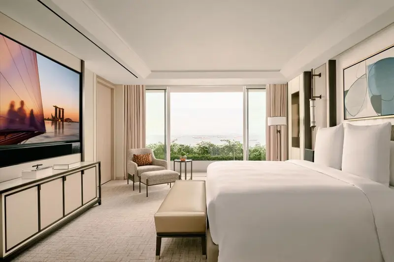 Chambre lumineuse avec un grand lit et une vue sur la mer.