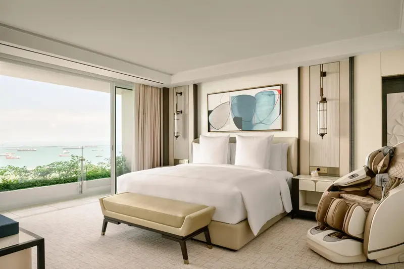 Chambre lumineuse avec un grand lit et une vue sur la mer.