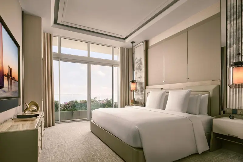 Une chambre lumineuse avec un grand lit et une vue sur la végétation.