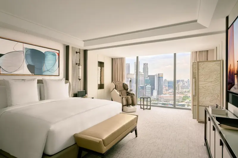 Chambre lumineuse avec un grand lit et une vue sur la ville.