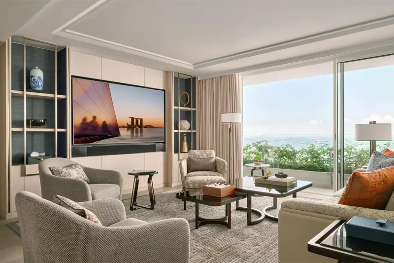 Un salon lumineux avec canapés et fauteuils face à une grande baie vitrée.