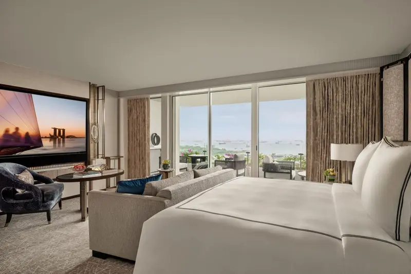Une chambre lumineuse avec un grand lit et un espace salon donnant sur une vue panoramique.